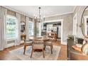 Dining room featuring a round wood table, decorative mirror, and a glimpse into the bright kitchen at 575 E Main St, Buford, GA 30518