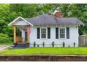 Charming single-story home with a covered porch, American flag, and freshly cut lawn surrounded by mature trees at 575 E Main St, Buford, GA 30518
