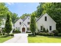Charming two-story white home featuring manicured landscaping, a curved driveway, and a beautiful arched wooden front door at 803 Courtenay Ne Dr, Atlanta, GA 30306