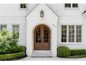 Close up of the charming arched wooden front door of the brick home, adorned with manicured shrubbery at 803 Courtenay Ne Dr, Atlanta, GA 30306