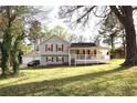 Traditional home with a cozy front porch, red shutters, and a well-manicured lawn in a serene, tree-lined setting at 24 Lady Savannah Dr, Dallas, GA 30157