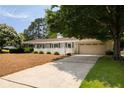 Lovely home showcasing an attached two-car garage, well-maintained driveway, and lush landscaping at 1100 Tuxedo Dr, Roswell, GA 30075