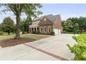 Long driveway leading to a brick home with a columned front porch and a three-car garage at 1565 Briergate Dr, Duluth, GA 30097