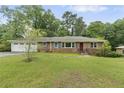 Charming brick home with a lush green lawn and mature trees providing shade at 2720 Birchwood Sw Way, Marietta, GA 30060