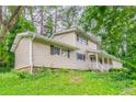 Side view of home showing neutral siding, covered front porch and lush greenery at 4715 Wildginger Run, Lithonia, GA 30038