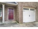 Close-up of brick-front home with garage and burgundy front door at 222 Ben Ln, Fairburn, GA 30213