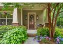 Inviting front porch with a rustic wooden door framed by blooming hydrangeas and charming exterior lighting at 1184 Medlin Se St, Smyrna, GA 30080