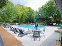 Community pool with lounge chairs, tables, and umbrellas surrounded by mature trees at 382 Winston Circle Cir, Canton, GA 30114