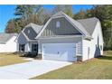 View of a charming home featuring a two-car garage and a well-maintained green lawn, set against a clear sky at 490 Charleston Pl, Villa Rica, GA 30180