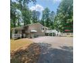 Exterior angle showing carport, a large deck with umbrella-covered seating area at 976 Bakers Bridge Rd, Douglasville, GA 30134