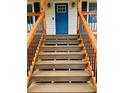 A detailed view of the home's entry stairs leading up to a covered front porch with a vibrant blue door at 112 Village Ct, Woodstock, GA 30188