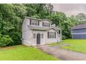 Quaint two-story home has a cozy front porch, grassy lawn, and delightful curb appeal at 6114 Leverett Dr, Lithonia, GA 30038