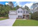 Two-story home showcasing stone accents, neutral siding, a well-manicured lawn, and a two-car garage at 492 Charleston Pl, Villa Rica, GA 30180