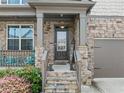 Inviting front porch with stone pillars and trim, steps to front door with HOME sign and comfortable seating at 4568 Mantova Dr, Buford, GA 30519
