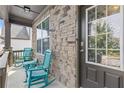 Charming front porch boasts stone accents and cozy blue rocking chairs, providing a welcoming entrance at 4568 Mantova Dr, Buford, GA 30519