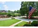 Beautiful street view featuring mature trees, manicured lawns, and traditional homes with an American flag at 830 Cramac Dr, Lawrenceville, GA 30046