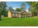 Inviting one-story home featuring a manicured lawn, classic shutters, front porch, and mature landscaping at 3690 Basswood Rd, Snellville, GA 30039