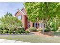 Well-maintained brick home featuring a landscaped front yard with mature trees and shrubs at 3284 Bakers Mill Ct, Dacula, GA 30019