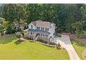 Two-story house with a covered front porch, featuring a well-manicured lawn, mature trees, and a long driveway at 226 Nacoochee Dr, Woodstock, GA 30188
