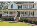 Charming home showcases a welcoming covered porch, complemented by stone accents and a well-maintained front lawn at 226 Nacoochee Dr, Woodstock, GA 30188
