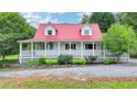 Inviting home with a red roof, dormer windows, a spacious wrap-around porch, and landscaped front at 1365 Lower Creighton Rd, Cumming, GA 30028