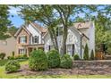 Charming two-story home featuring stone accents, white siding, and mature landscaping at 300 Windsor Chase Trl, Johns Creek, GA 30097