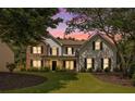 Charming two-story home featuring stone accents, white siding, and a well-manicured front yard at sunset at 300 Windsor Chase Trl, Johns Creek, GA 30097