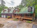 Picturesque log cabin featuring a connecting garage, wood porch, and green roof at 519 E Valley Ne Rd, Rydal, GA 30171