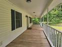 Inviting front porch featuring wood flooring, white railings, and exterior wall lighting at 8291 Highway 5, Whitesburg, GA 30185