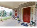 Inviting front porch with seating, a red front door, and charming decorations that add a welcoming touch at 893 Whitfield Oak Rd, Auburn, GA 30011