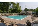 Community pool with plenty of lounge chairs, umbrellas and a clubhouse in a wooded area at 208 Oconee Way, Canton, GA 30114