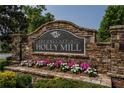 Stone entrance sign for The Enclave at Holly Mill, surrounded by flower beds and landscaping at 208 Oconee Way, Canton, GA 30114