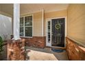 Close-up of the front door featuring brick accents, a decorative wreath, and a welcoming entrance at 208 Oconee Way, Canton, GA 30114