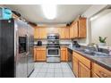 Functional kitchen with stainless steel appliances, wooden cabinetry, and a tiled floor for easy maintenance at 502 Gallantry Trl, Mcdonough, GA 30252