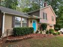 Charming split-level home featuring manicured shrubs, a bright front door, and a blend of siding and brick at 4678 Browns Mill Ferry Rd, Lithonia, GA 30038