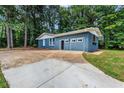 Blue brick home with a spacious driveway and garage, surrounded by lush trees at 4756 Fellsridge Dr, Stone Mountain, GA 30083
