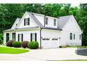 Three car garage featuring black shutters, green landscaping and well manicured lawn at 7037 Tara Dr, Villa Rica, GA 30180