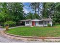Charming single-story home featuring a well-manicured lawn, complemented by a bright red front door and a covered carport at 4922 Glenside Ct, Stone Mountain, GA 30088