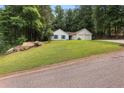 View of a white house with blue shutters, a green lawn, and mature trees surrounding the property at 506 Bluff Ct, Woodstock, GA 30188