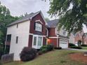View of the side of the two-story home with brick and white siding and an attached garage at 1033 Hawk Creek Trl, Lawrenceville, GA 30043