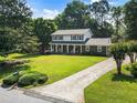 An inviting two-story home with a long driveway, complemented by lush greenery and mature trees at 385 Stonebridge Trl, Roswell, GA 30075