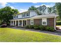 Traditional home with a welcoming covered porch, brick accents, and well-maintained landscaping at 385 Stonebridge Trl, Roswell, GA 30075
