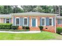 A cozy brick home with blue shutters and door, complemented by a well-maintained lawn and landscaping at 1744 Chateau Dr, Dunwoody, GA 30338