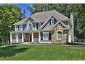 Inviting two-story home with a stone facade, covered porch and landscaped front yard at 6425 Riley Manor Way, Cumming, GA 30028