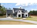 Charming two-story home featuring a white brick facade, dark roof, long driveway, and lush green lawn at 115 Palisade Dr, Rydal, GA 30171