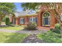Close up of the front exterior brick home featuring an arched entry, blue shutters, and manicured lawn at 718 First Cotton Dr, Powder Springs, GA 30127