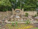 Stone waterfall feature with mature landscaping at the entrance of the Falls of Autry Mill community at 9745 Autry Falls Dr, Alpharetta, GA 30022