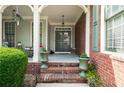 Charming covered front porch with brick accents and decorative potted plants at 1290 Magnolia Park Cir, Cumming, GA 30040