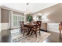 Formal dining room featuring wainscoting, a modern chandelier, a wooden dining table, and large windows at 4030 River Ridge Se, Marietta, GA 30067
