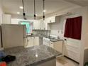 Bright kitchen featuring granite countertops, white cabinets, and modern lighting fixtures at 186 W Lake Nw Dr, Atlanta, GA 30314